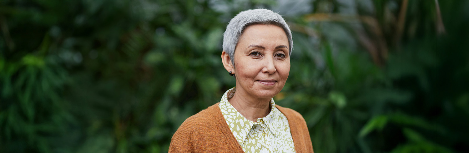 A person smiles softly at the camera in an outdoor setting. The background is blurred. The image conveys the value of clear government communication.