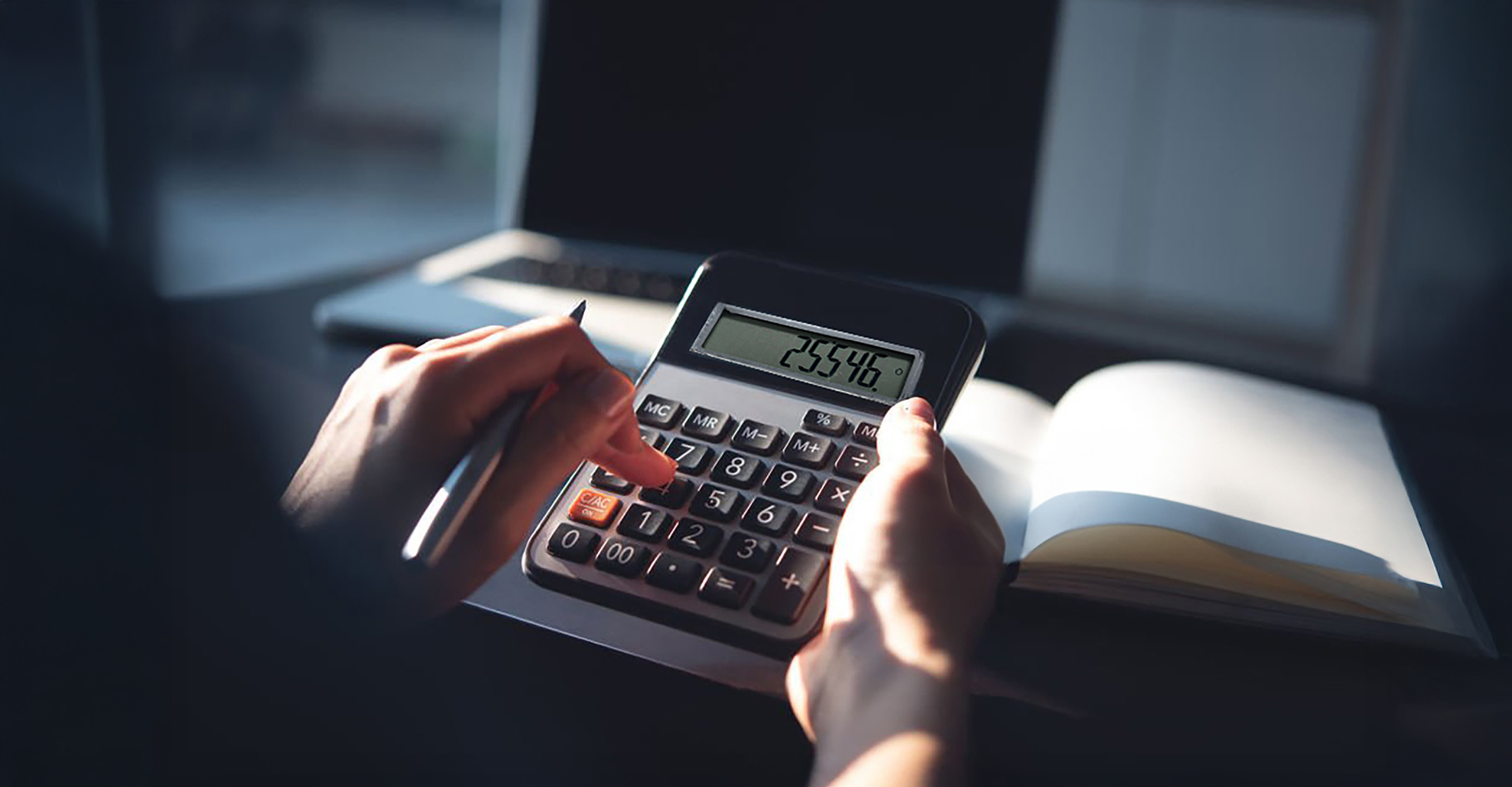 Person typing on a calculator, the number 25,546 on the screen.