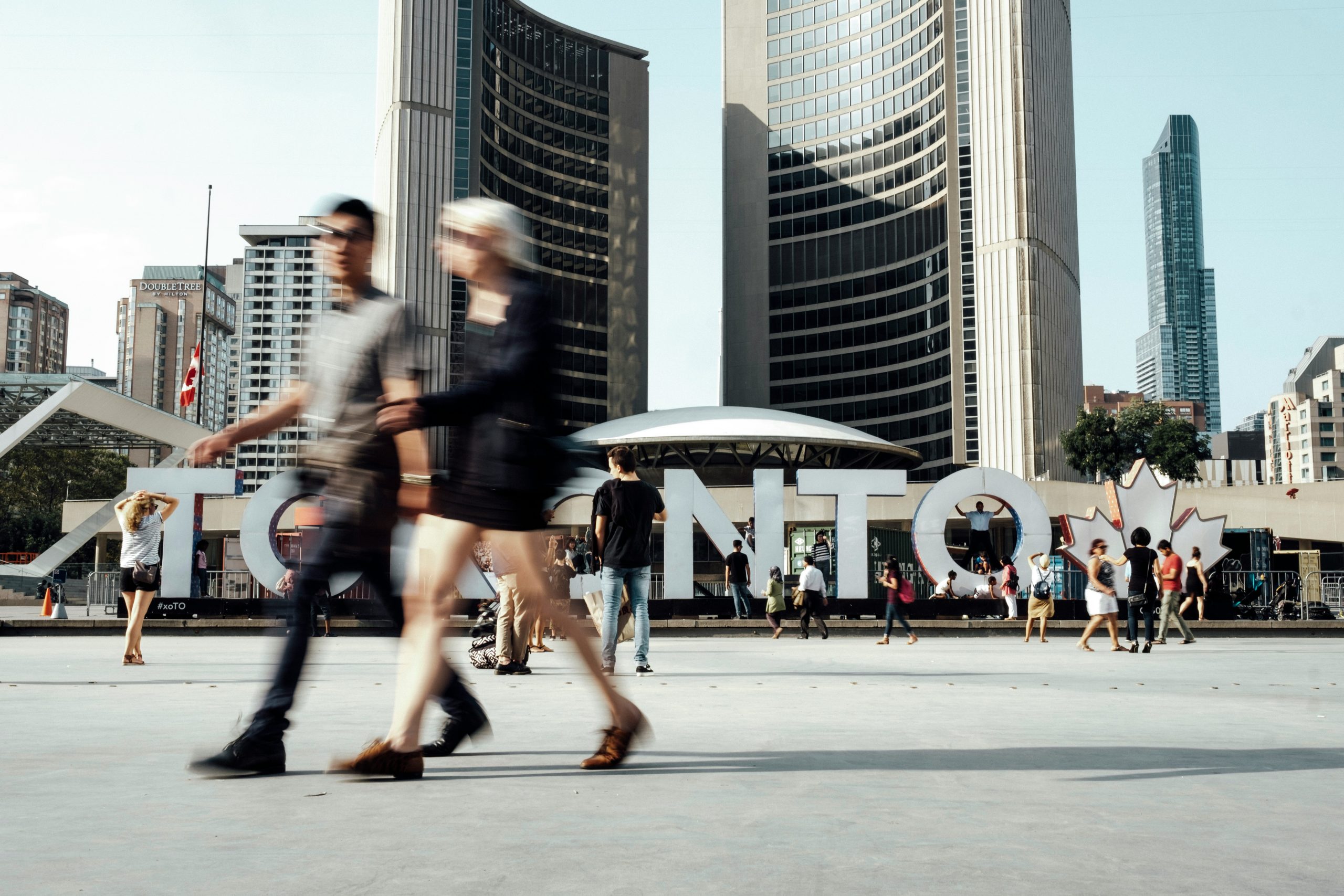 People milling around in front of City Hall, the Toronto sign in the backgruond.