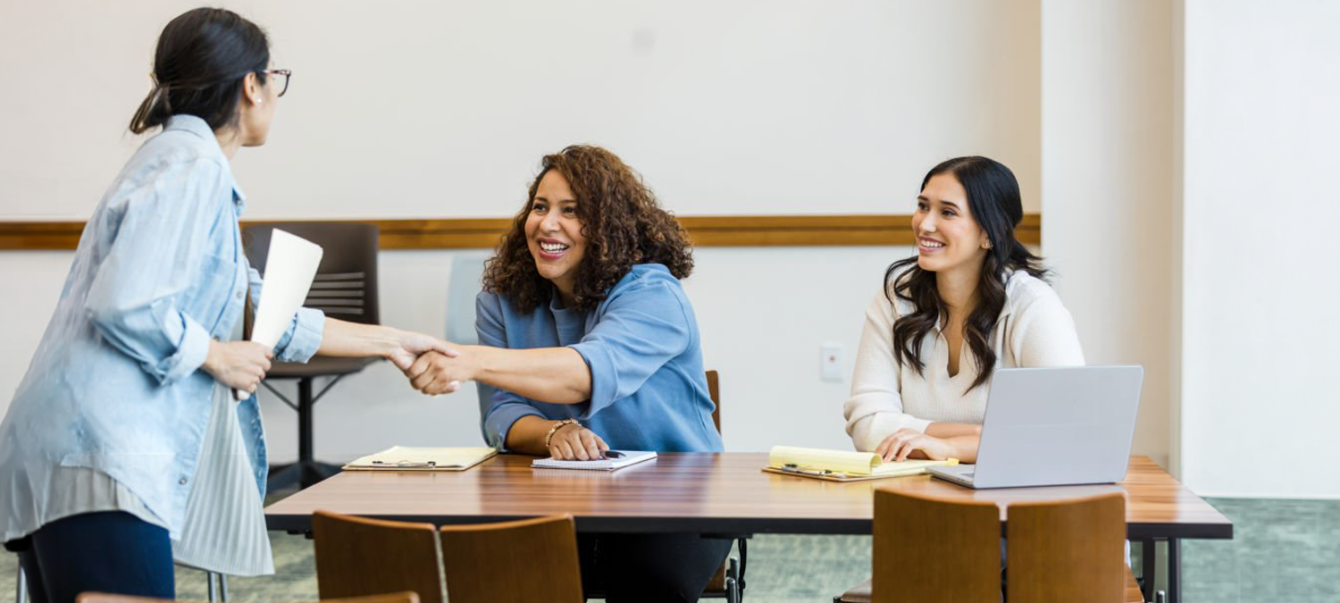 An interview panel shakes the hand of a candidate