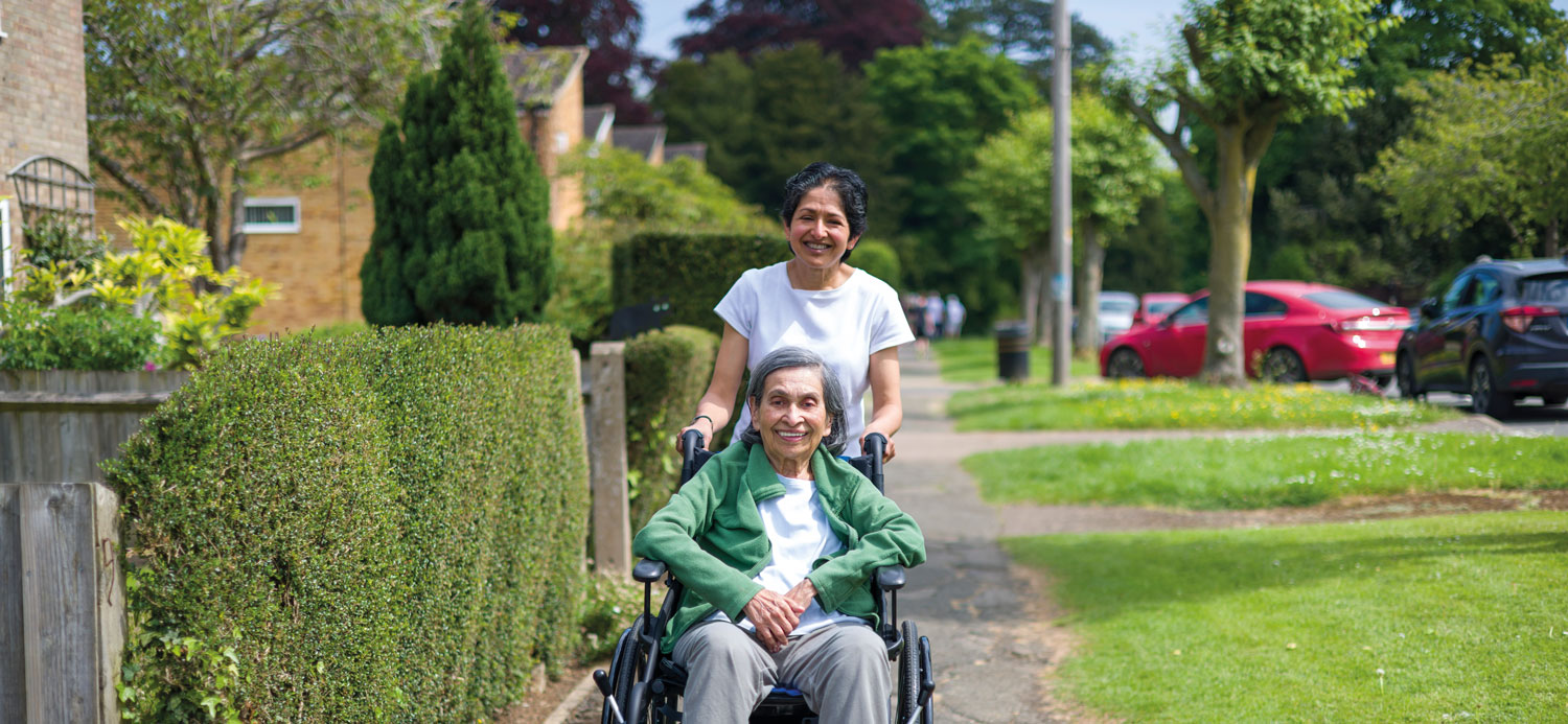 A woman in a wheelchair is being pushed by another woman.