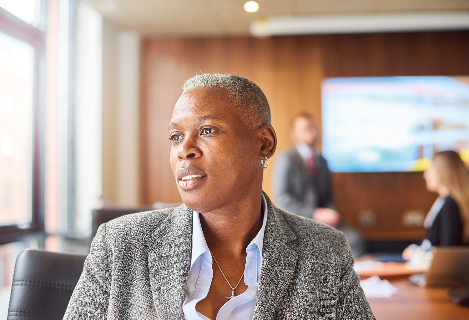 A woman in a grey jacket and white shirt.