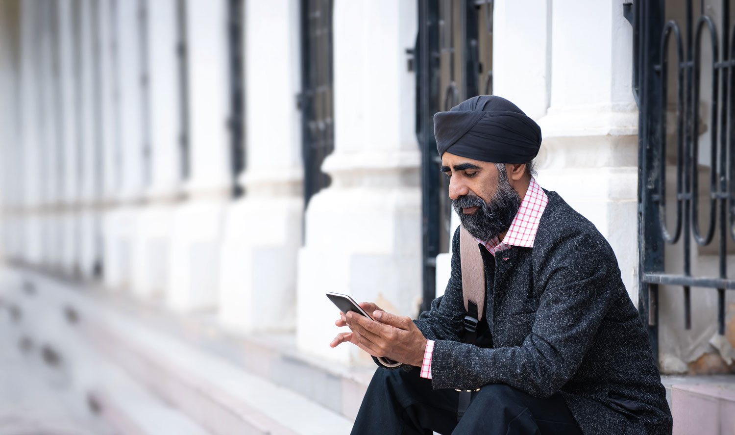 A man sitting on a step looking at his cell phone.