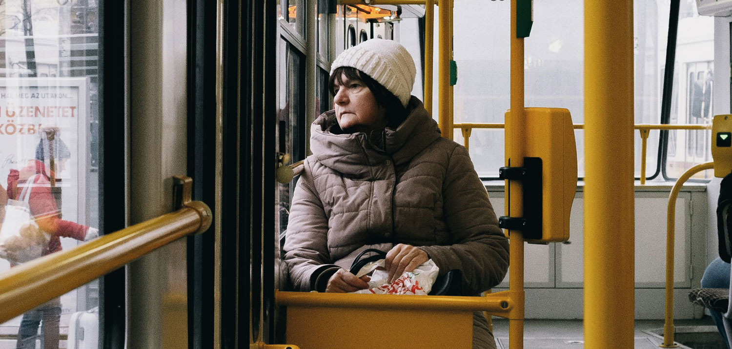A person is sitting on a streetcar, looking out the window